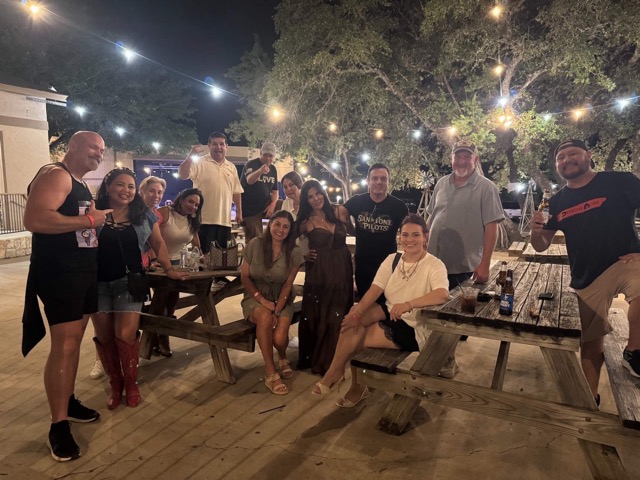 Festival-goers gathered at picnic tables under string lights and live oaks at Rocklobster Fest, Josabi's, Helotes, Texas